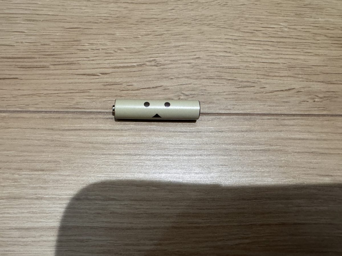 ダンボー柄の単4形充電池。金色の胴に、目と口を表した2つの丸と三角が描かれている