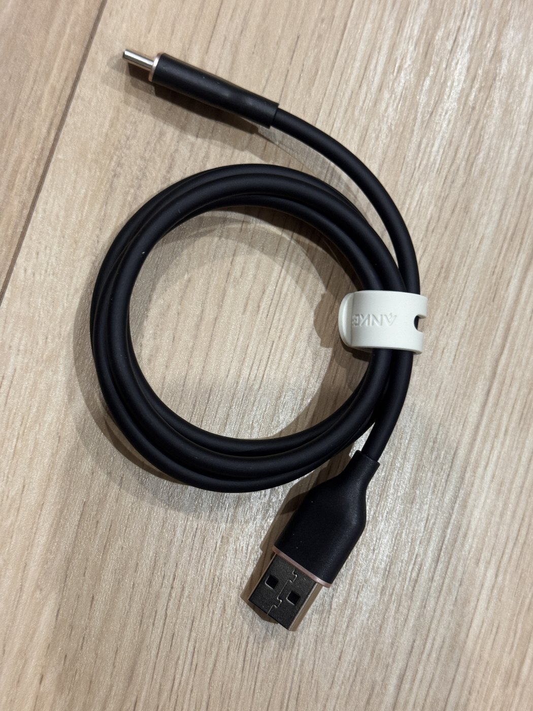 床に置いた黒いAnker Flowケーブル。白い結束バンドでまとめられ、素直な輪になっている