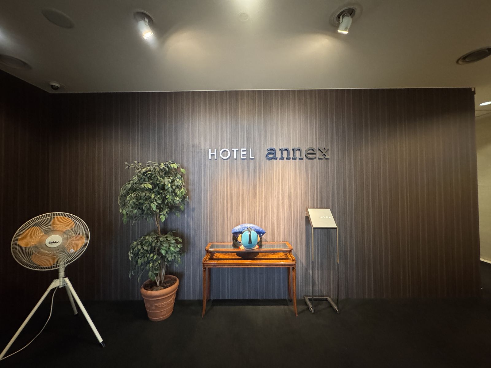 ホテル アネックスのロゴが付いた壁と、観葉植物の置かれた館内