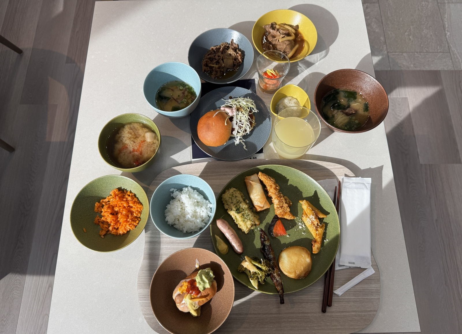 朝食の和定食。ごはん、味噌汁、焼き魚、小鉢がいくつか、オレンジジュース