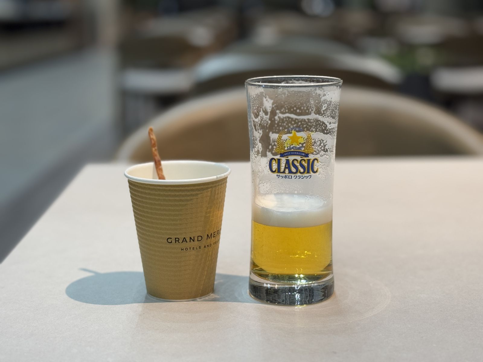 注いだビールのグラスと、ホテルのロゴが入った紙コップ