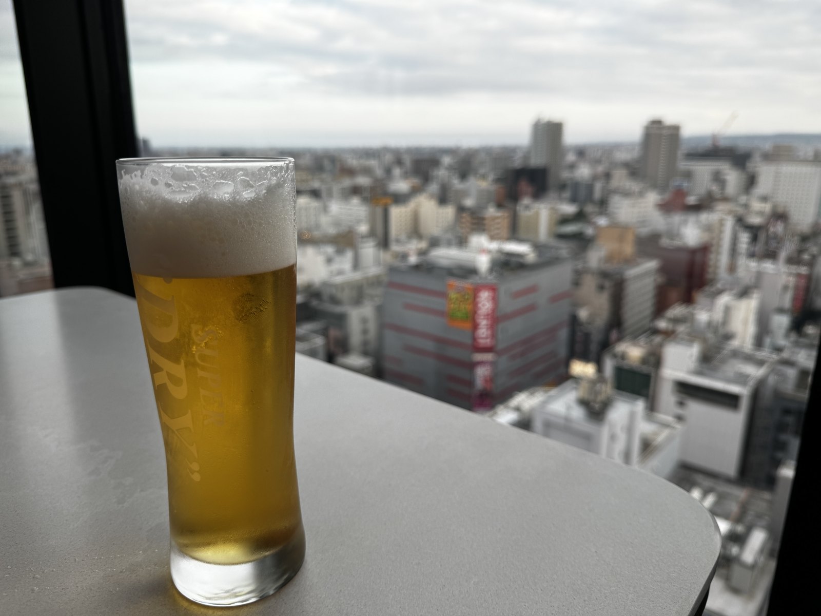 ラウンジのテーブルに置かれたビール。窓の外に札幌の街が広がる