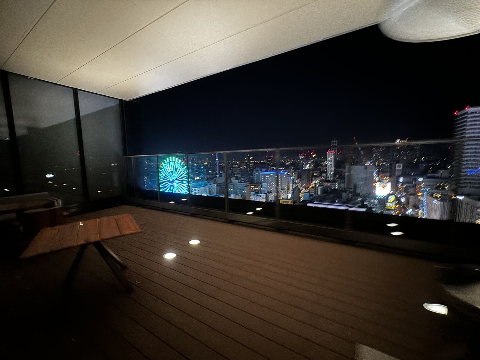 ホテルの屋上テラス。ウッドデッキの向こうに夜景が広がっている