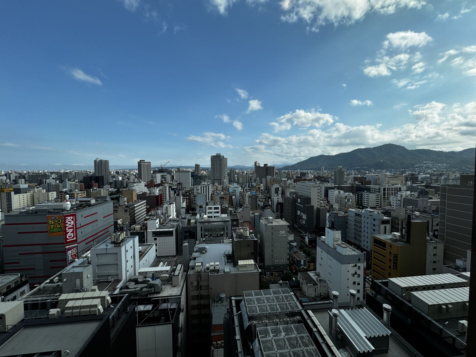 客室から見た昼の札幌。ビルの向こうに山が見える
