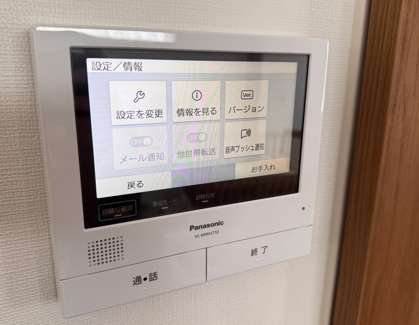 壁に取り付けられたパナソニックの白いインターホンの室内モニター。画面に設定の項目が並び、下に通話と終了のボタンがある