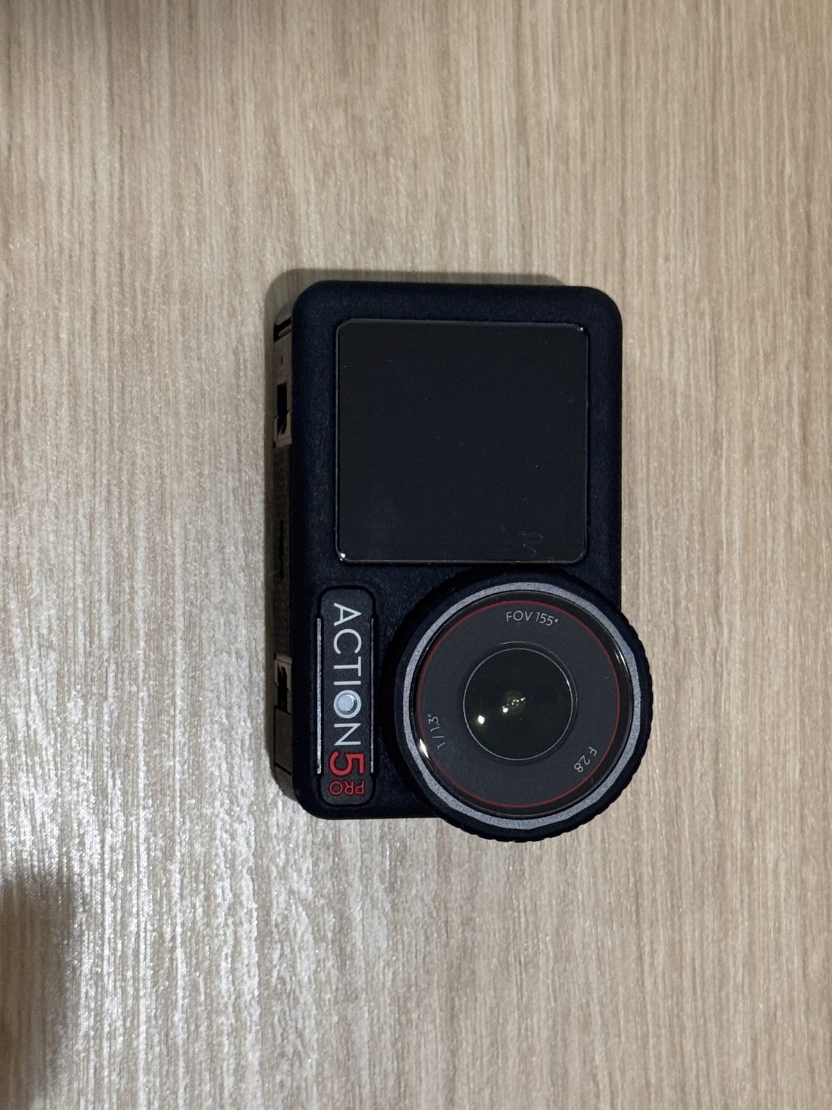 床に置いたDJI Osmo Action 5 Proの本体。前面の小さなディスプレイに ACTION 5 PRO と表示されている
