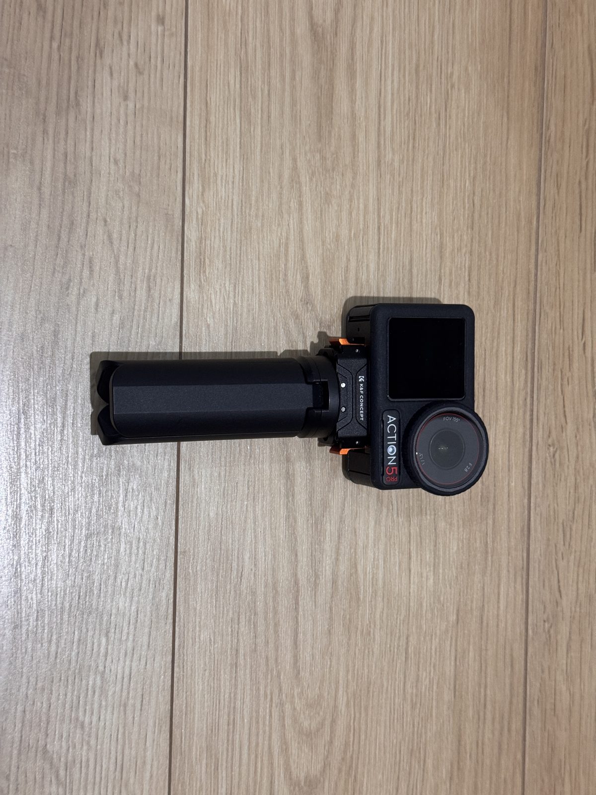 Osmo Action 5 Proをマウントとグリップに取り付けて組み上げた状態。黒い棒状のグリップの先にカメラが横向きに付いている