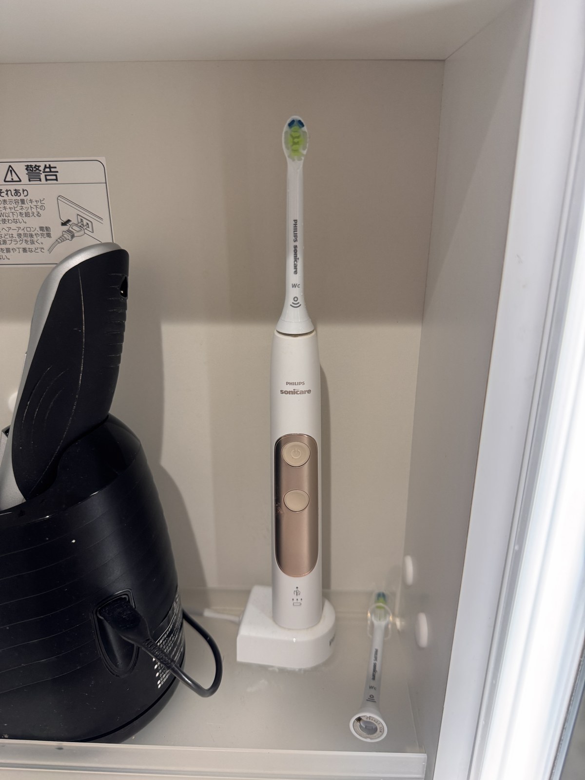充電スタンドに立てた白いソニッケアー エキスパートクリーンの本体。持ち手にローズゴールドのボタンが2つ並んでいる