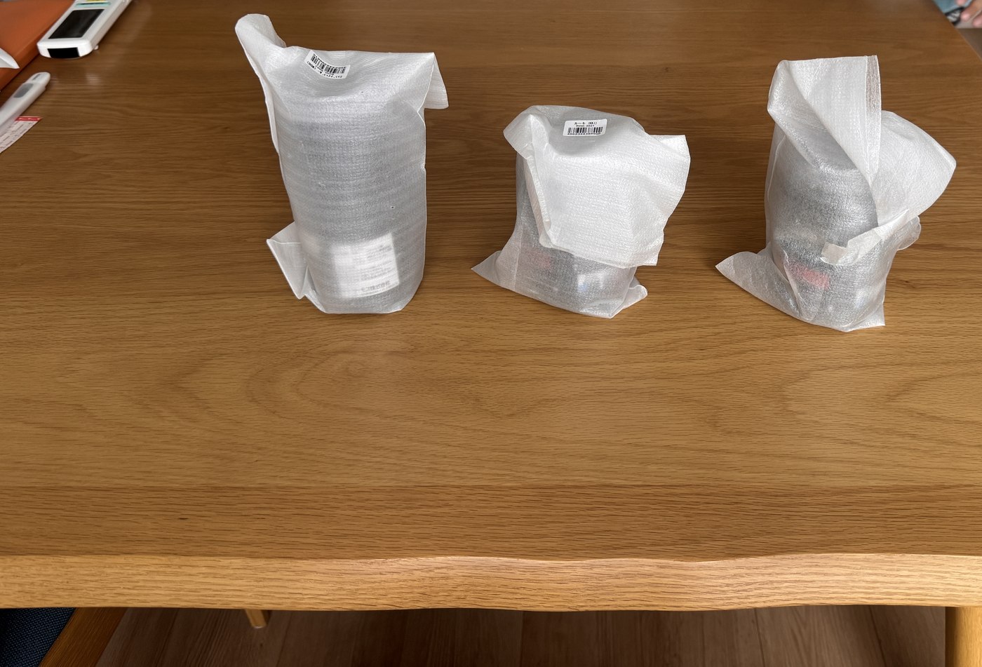 白い緩衝材の袋に入ったまま机に並べられた保冷缶ホルダー3個。箱は無い