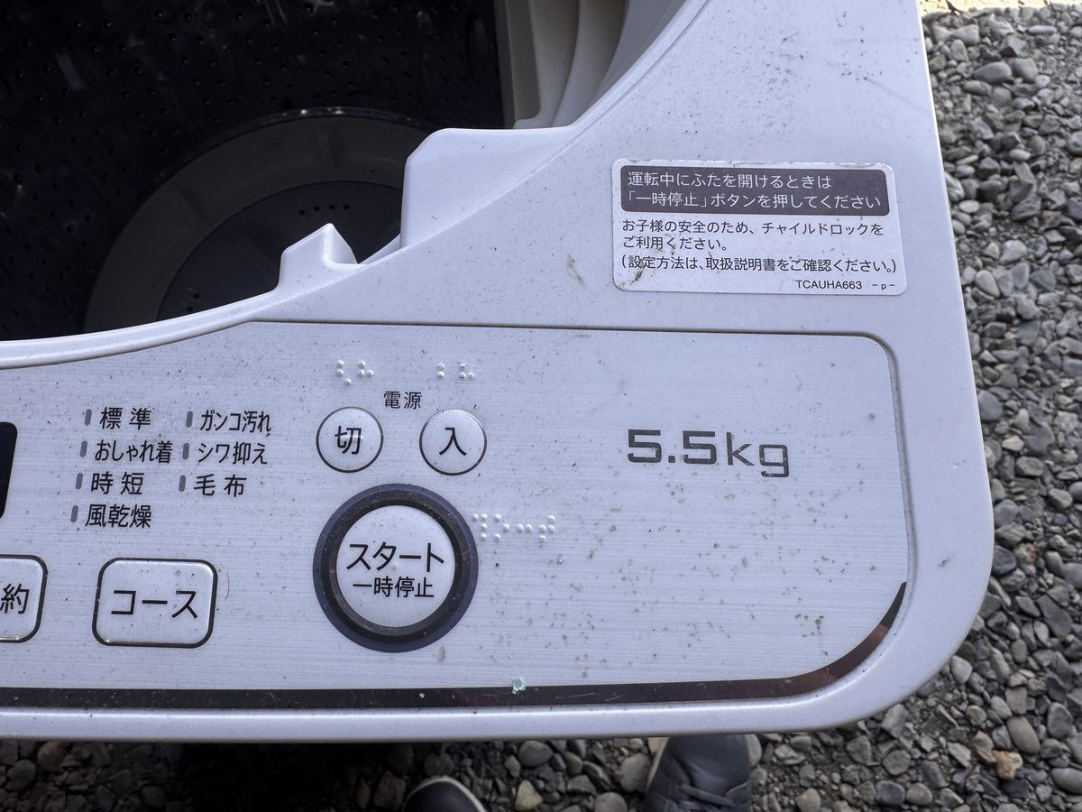前の縦型洗濯機の操作パネル。標準・ガンコ汚れ・おしゃれ着・シワ抑え・時短・毛布・風乾燥のコースと、5.5kgの表示