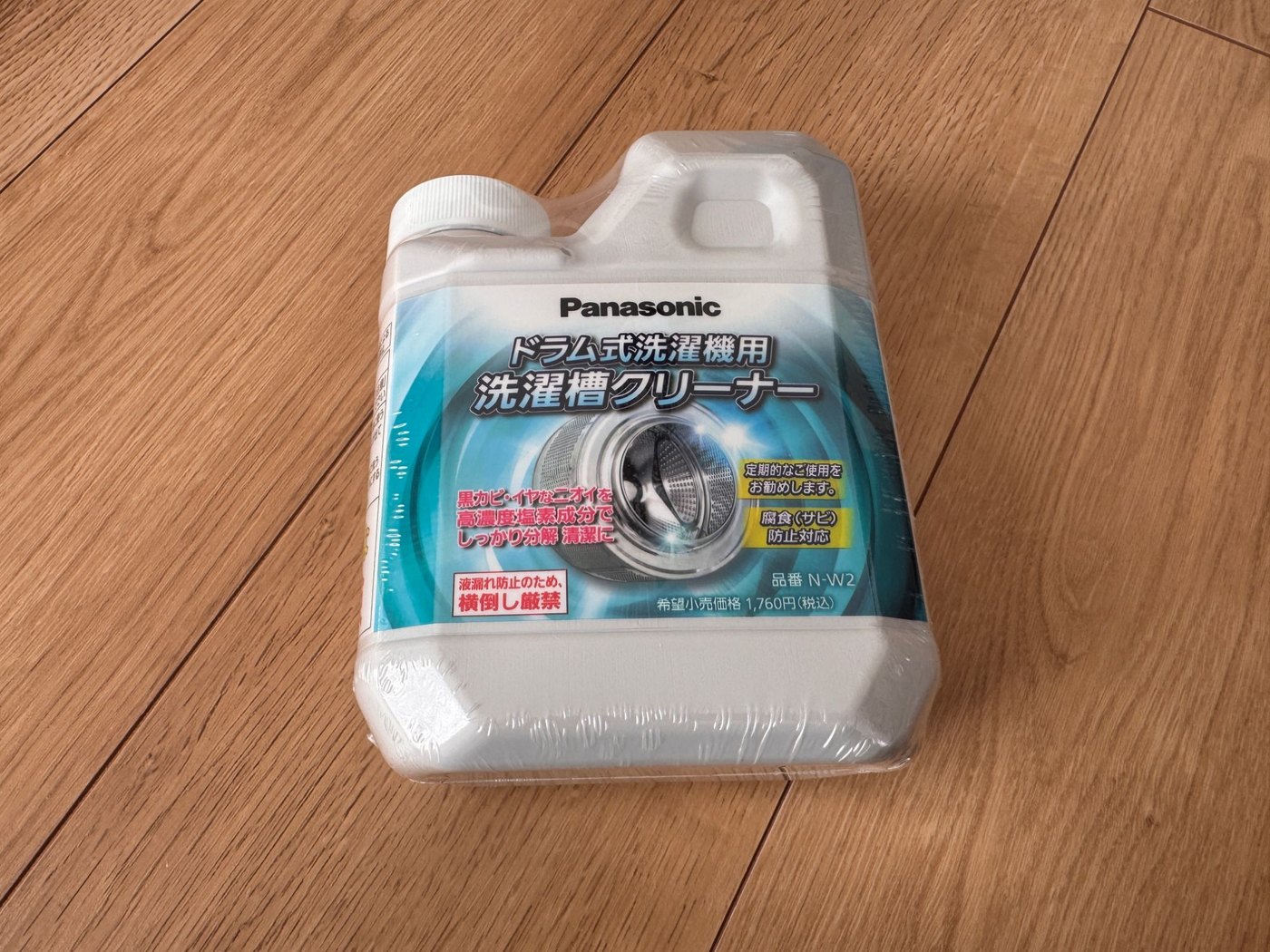 木の床に置いたパナソニックのドラム式洗濯機用 洗濯槽クリーナー N-W2。白いボトルに水色のラベルが巻かれている